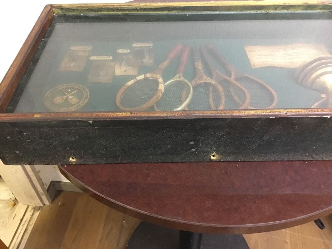 アンティークなテニスラケットの歴史と変遷について解説している彫刻が収められた額装